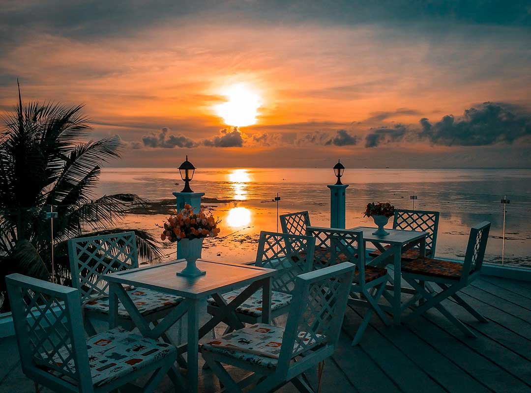 Beach sunset with a table and chairs near a palm tree